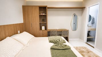 Quarto com cama, escrivaninha, armário, espelho e banheiro.