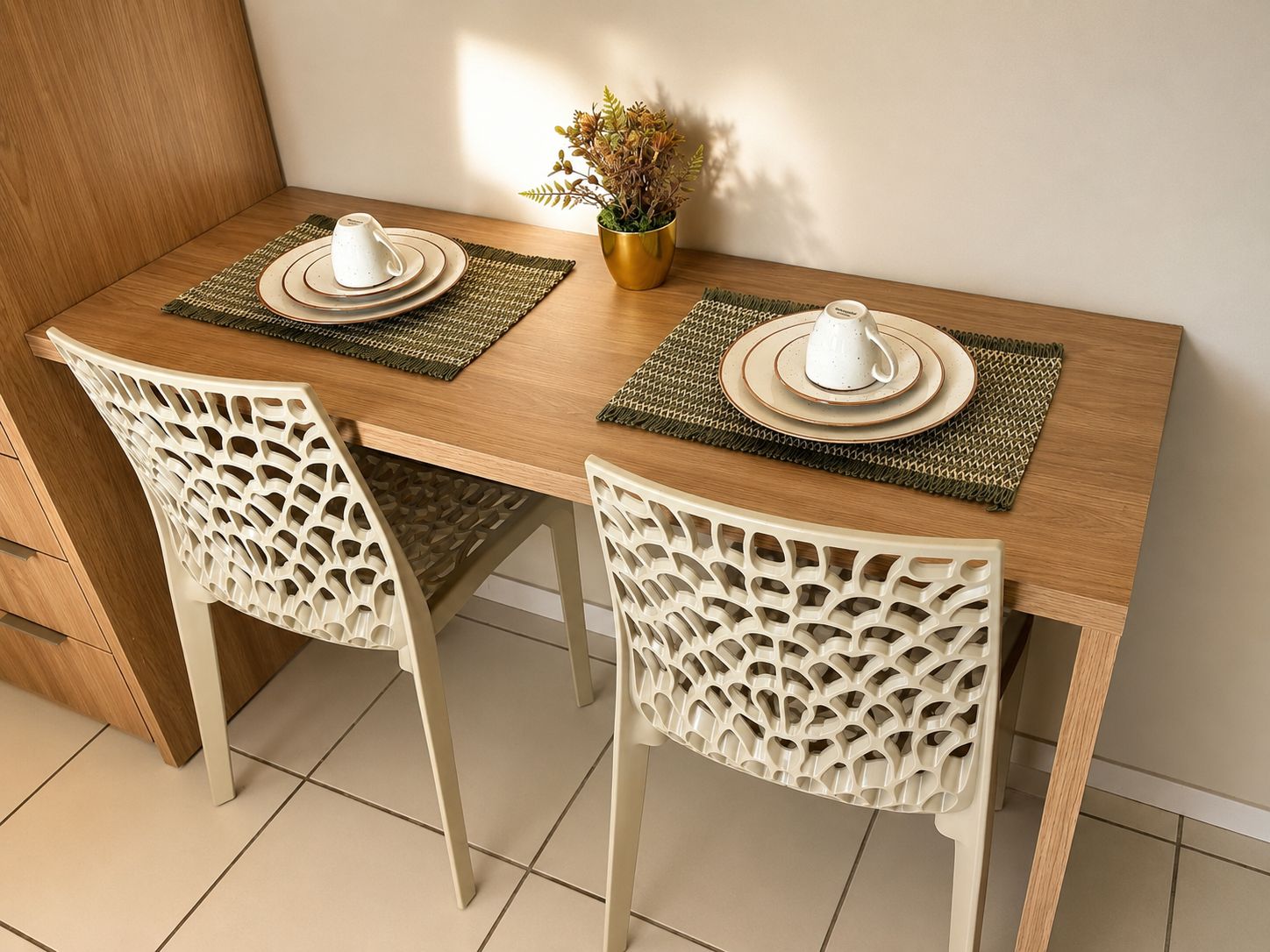 Een eettafel met twee stoelen, een plant en een gedekte tafel.