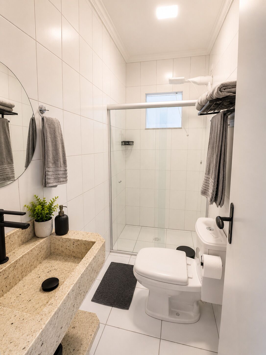 Een moderne badkamer met een douchecabine van glas, een wit toilet en een granieten wastafel.