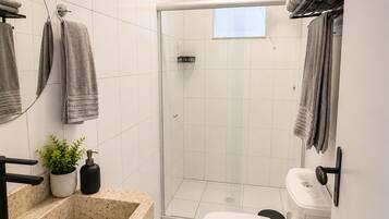 Een moderne badkamer met een douchecabine van glas, een wit toilet en een granieten wastafel.