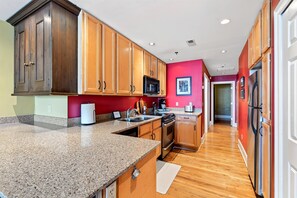 Eine Küche mit Holdekor-Schränken, Granit-Arbeitsplatten, einem Edelstahl-Kühlschrank und einer Mikrowelle.