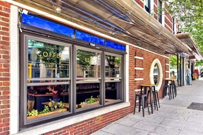 Ein Backsteinhaus mit einer Schaufensterfront, durch die ein Café einsehbar ist.