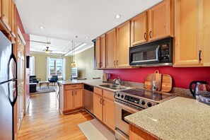 A modern kitchen with wooden cabinets, a stainless steel stove, and a microwave. - Historic Downtown Loft | Steps from S&W Food Hall & Drum Circle! (Asheville)