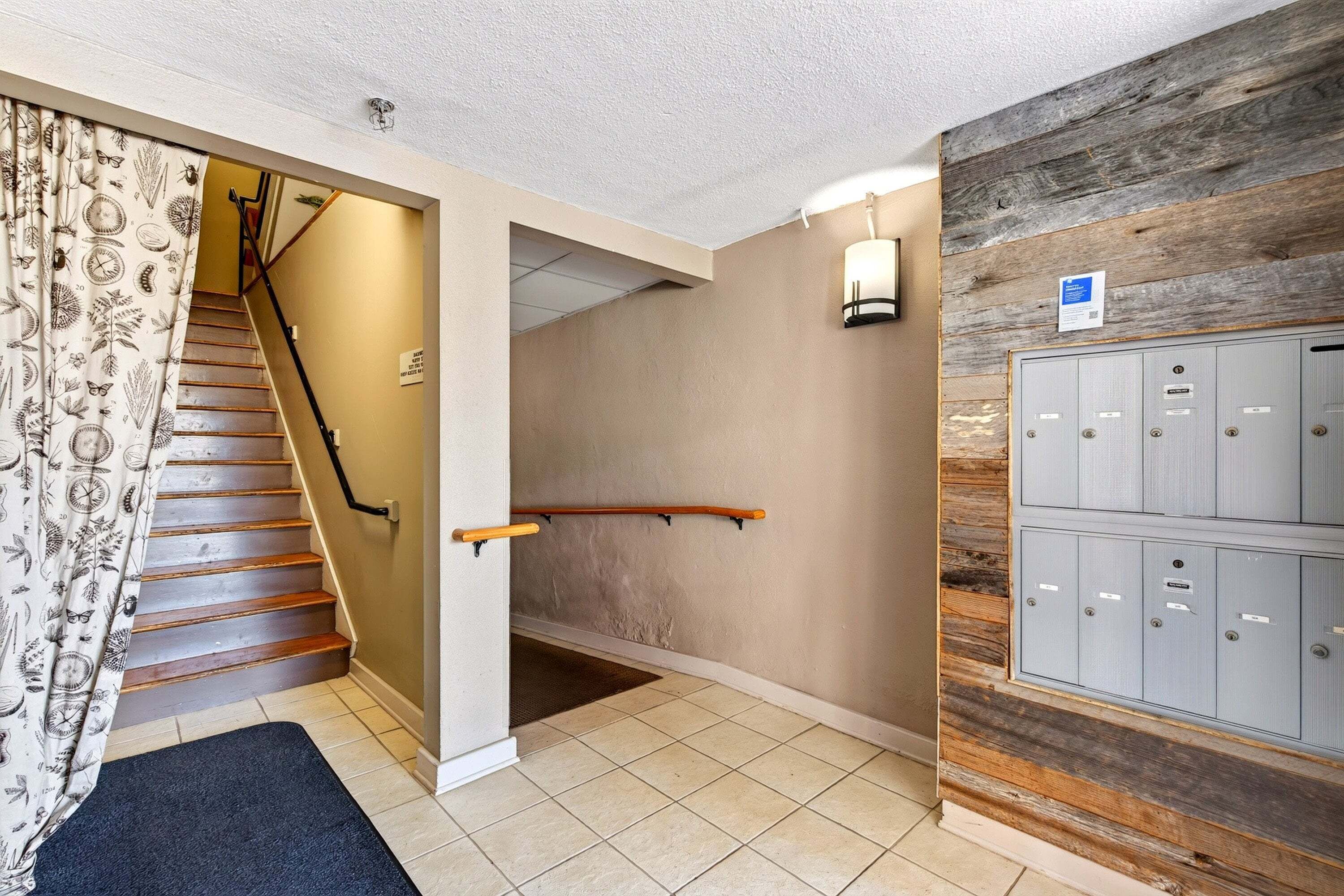 A staircase with a handrail, a wall-mounted light fixture, and a set of lockers.