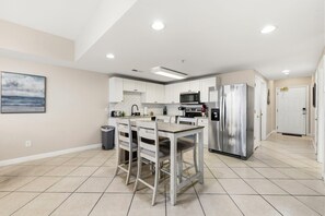 Une cuisine moderne avec des meubles blancs, des appareils en acier inoxydable et un sol carrelé.
