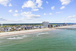 En kuststad med en strand, en pir och ett högt hotell.