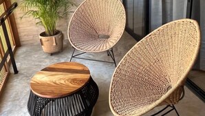 A modern outdoor seating area with two wicker chairs and a round wooden table.