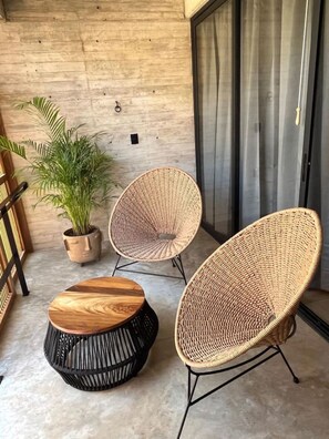 A modern outdoor seating area with two wicker chairs and a round wooden table.