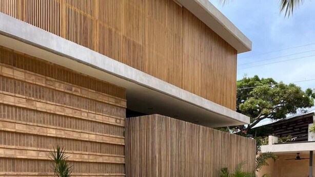 A modern building with a pool, wooden paneling, and a staircase leading to an upper level.