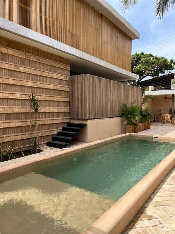 A modern building with a pool, wooden paneling, and a staircase leading to an upper level.