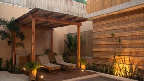 Un espace extérieur aménagé, abrité et doté de deux fauteuils, d’une petite table et d’un jacuzzi.