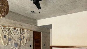 Un dormitori modern amb un llit, una panxa de fusta, decoració mural de borrons i un ventilador de sostre.