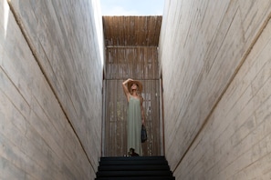 A person standing in a narrow corridor with wooden walls and a metal roof.
