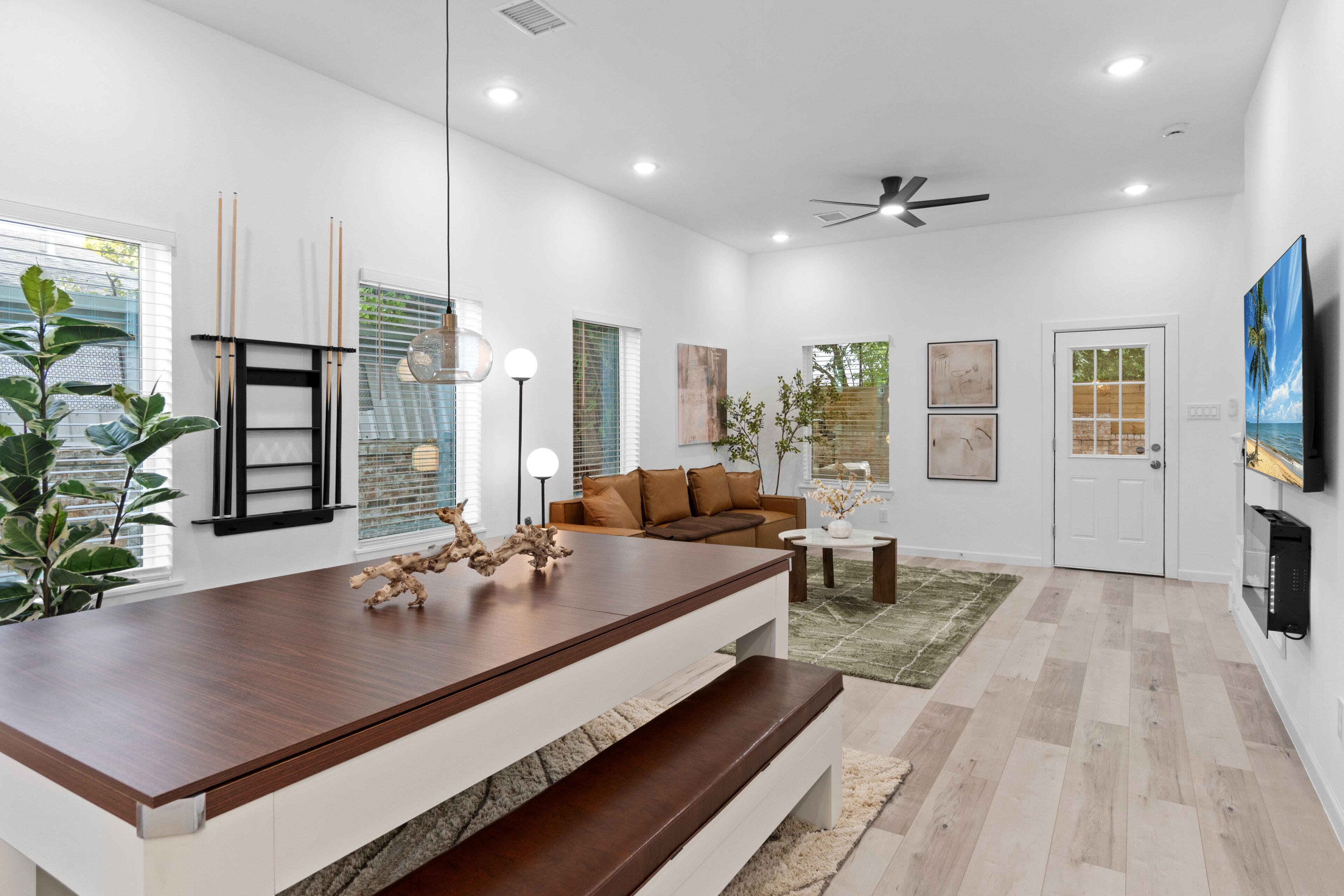 Una sala de estar moderna con una mesa de comedor de madera, un sofá marrón y un ventilador de techo.