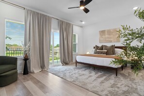 A bedroom with a bed, a ceiling fan, a window with curtains, a view of the outdoors, and a potted plant. - Houston 3BR Home - Arcade, Pool Table & Patio (Houston)