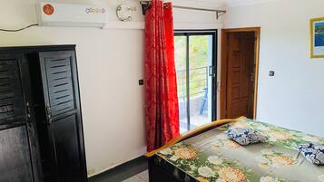 Een kamer met een bed, een kledingkast, een raam met rode gordijnen en een deur.