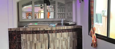 A modern kitchen with a marble countertop, a wooden backsplash, and a window above the sink.