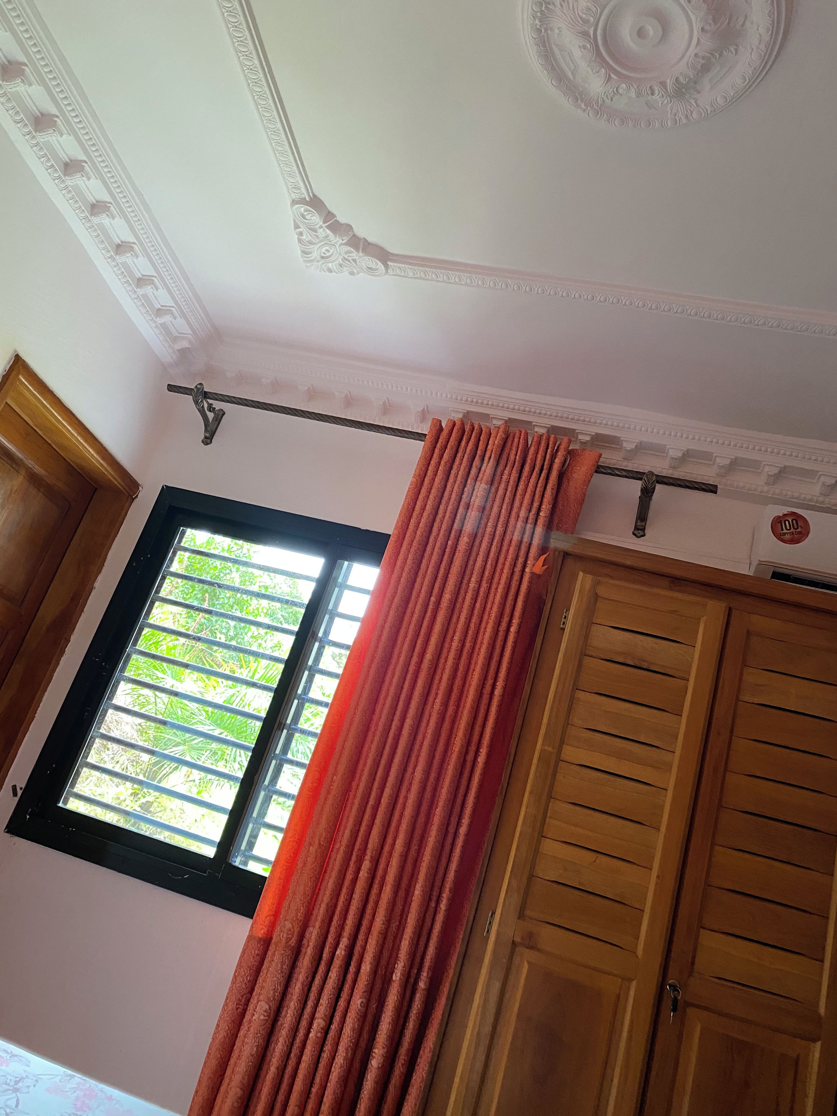 Una habitación con ventana, cortina y armario de madera.