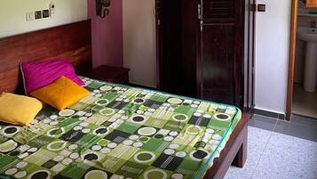 A bedroom with a bed, a wardrobe, a wall-mounted light, and a door leading to a bathroom.