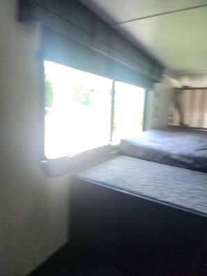 Een kamer met een bed, een raam en een gordijn.