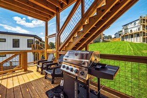 Eine Terrasse im Freien mit Grill, Stühlen und Blick auf eine Wohngegend.