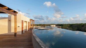 Ein Infinity-Pool auf dem Dach mit Holzterrasse und Blick auf die umliegende Landschaft.