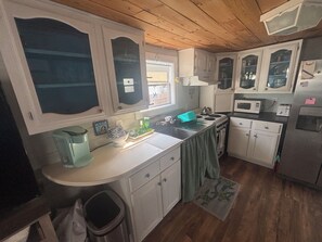 A kitchen with white cabinets, a stove, a sink, and a microwave. - Quaint 1-bedroom studio with AC in Oak Island - just a 1/2 mile to the beach! (Oak Island)