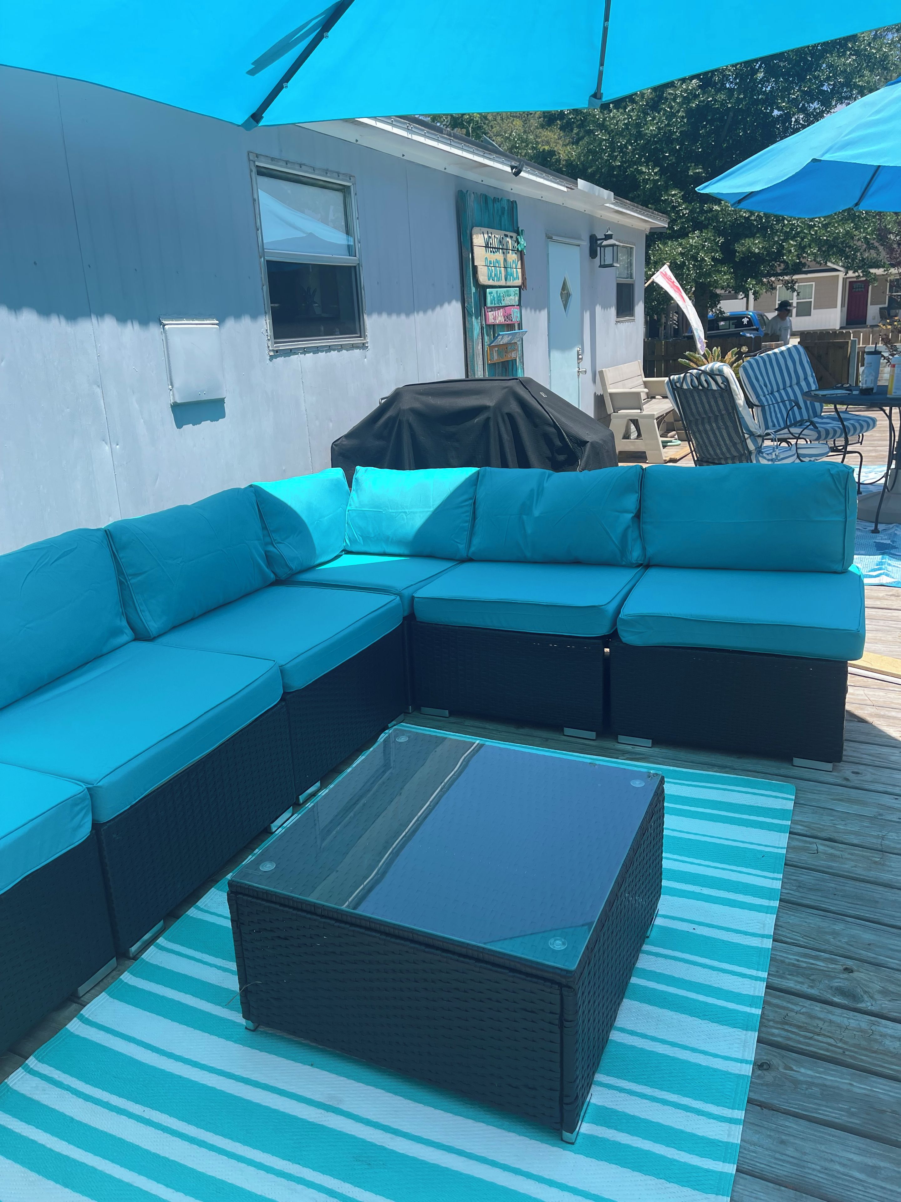 Ein Teil eines Bootes mit einer großen blauen Couch, einem kleinen Tisch und einem Grillbereich mit Abdeckung.