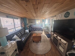 A cozy living room with a sofa, a coffee table, a TV, and a fireplace. - Quaint 1-bedroom studio with AC in Oak Island - just a 1/2 mile to the beach! (Oak Island)