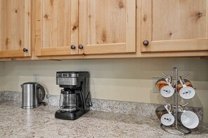 Eine Küche mit Holzschränken, einer Kaffeemaschine, einem Wasserkocher und einem Becherhalter.