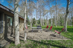 A patio area with a table and chairs, surrounded by trees and a building. - 7 minutes to Yellowstone The Aspen Cabin (West Yellowstone)