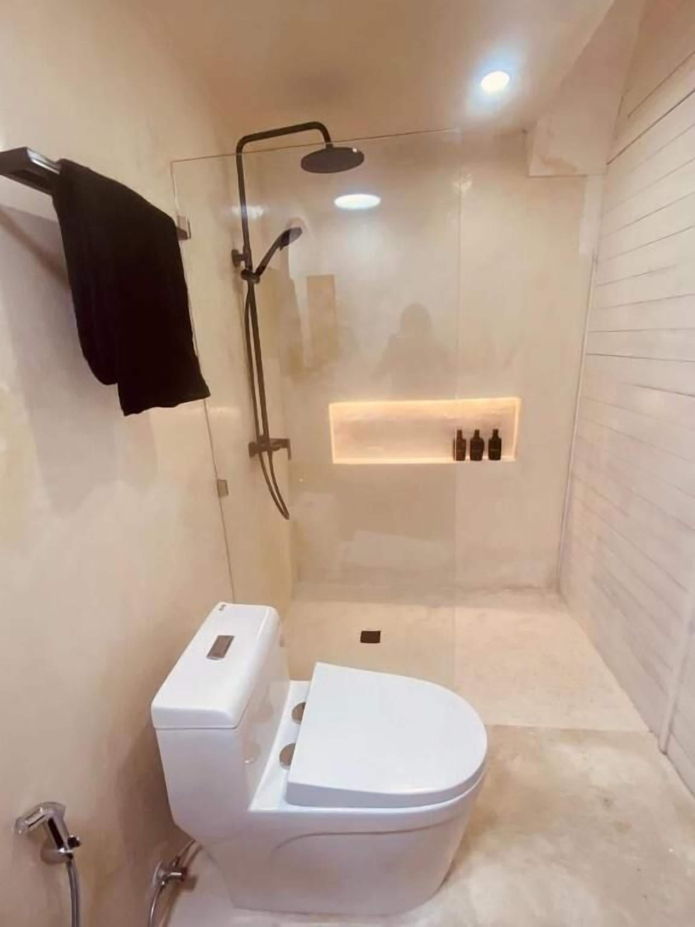 Un baño moderno con ducha envuelta en vidrio, inodoro blanco y barra para toallas.