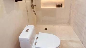 Un baño moderno con ducha envuelta en vidrio, inodoro blanco y barra para toallas.