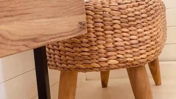 Un taburete tejido con patas de madera y un cajón con asa metálica.