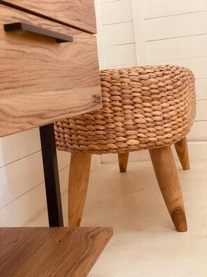 Un taburete tejido con patas de madera y un cajón con asa metálica.