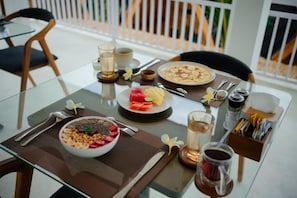 Taula de dinar amb esmorzar que inclou un bol de cereals, un plat de fruita, una tassa de cafè i un got d'aigua.