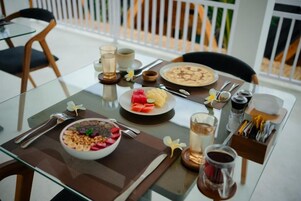 Una mesa de comedor con desayuno, que incluye un tazón de cereal, un plato de fruta, una taza de café y un vaso de agua.