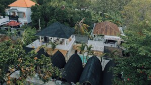 Un quartier résidentiel composé de plusieurs maisons, dont certaines sont dotées de toits de chaume, et entouré d’une végétation luxuriante.