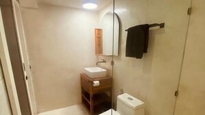 Une salle de bain avec une douche à parois de verre, des toilettes et un lavabo.