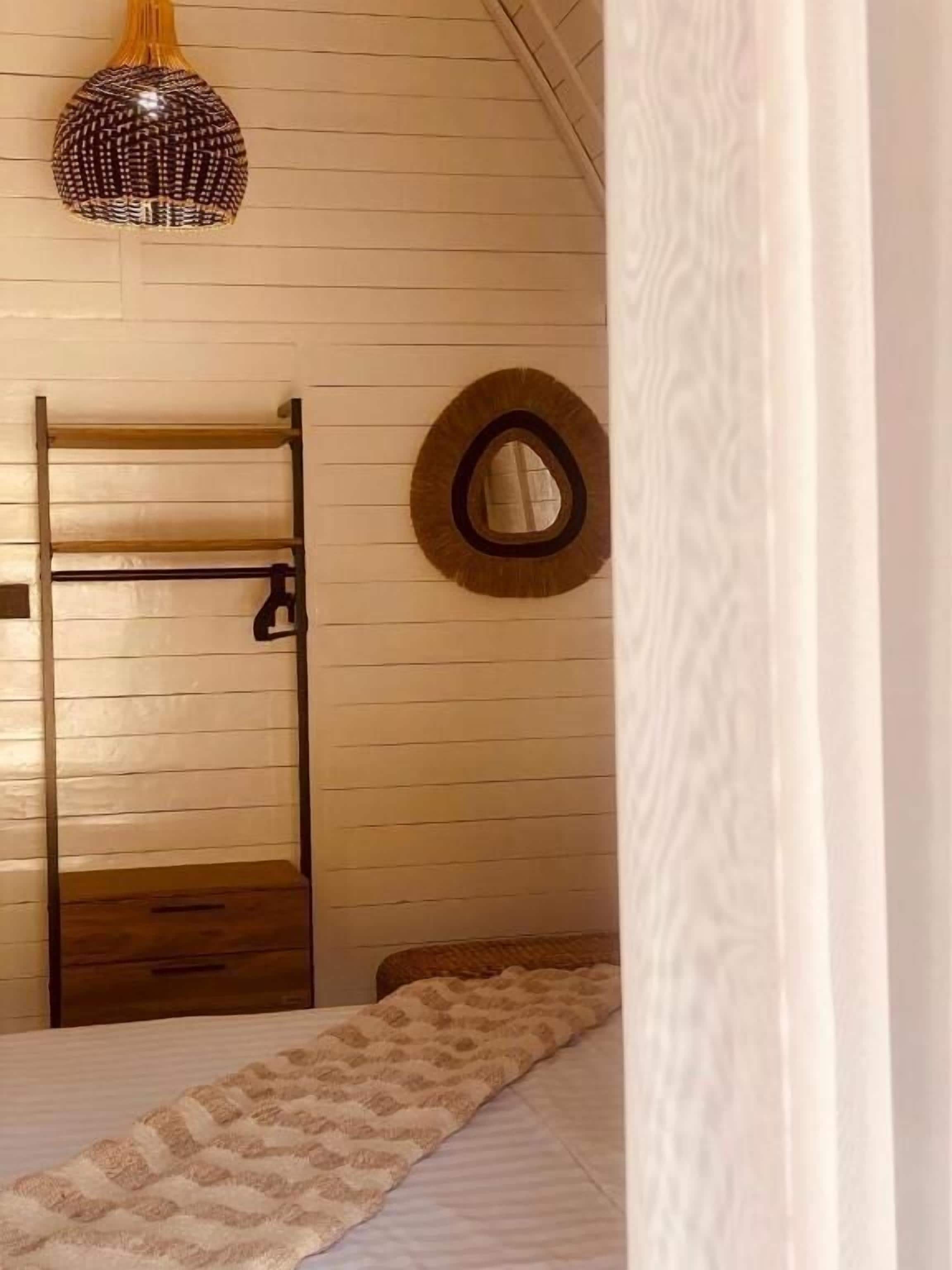 A room with a bunk bed, a ladder, a circular mirror, and a hanging light fixture.