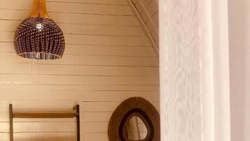 A room with a bunk bed, a ladder, a circular mirror, and a hanging light fixture.
