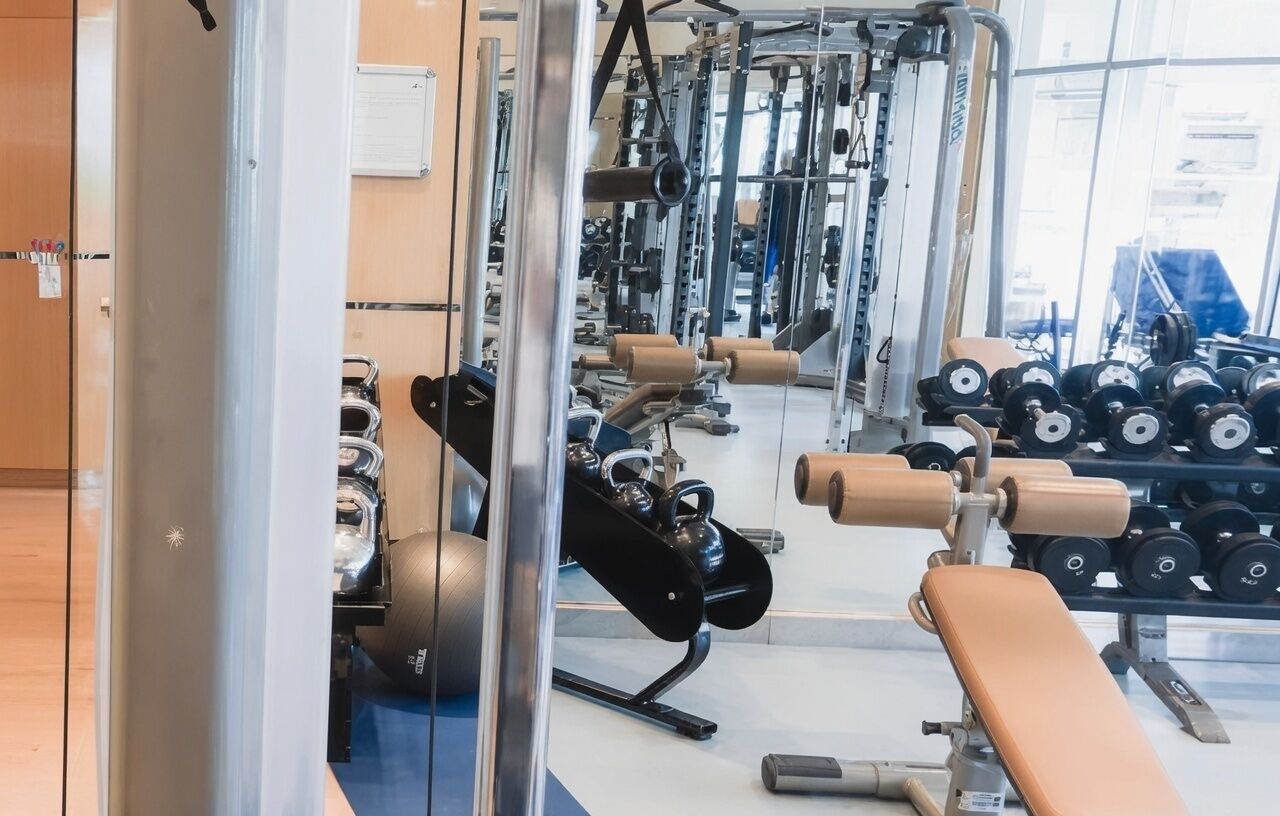 Een fitnessruimte met diverse trainingsapparaten, waaronder gewichten en kettlebells.
