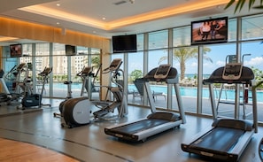 A gym with treadmills, ellipticals, and a pool view. - Luxury 1BR Ocean Heights, 64th Floor Panoramic Sea and Palm Views with Jacuzzi (Dubai)