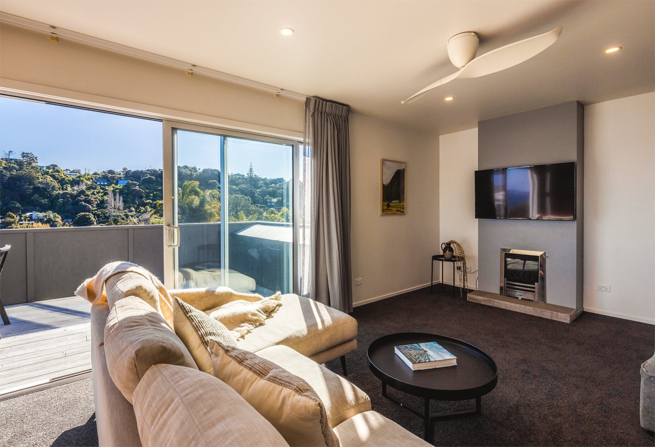 A modern living room with a sofa, a coffee table, a flat-screen TV, and a fireplace.
