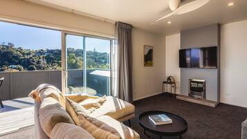 A modern living room with a sofa, a coffee table, a flat-screen TV, and a fireplace.