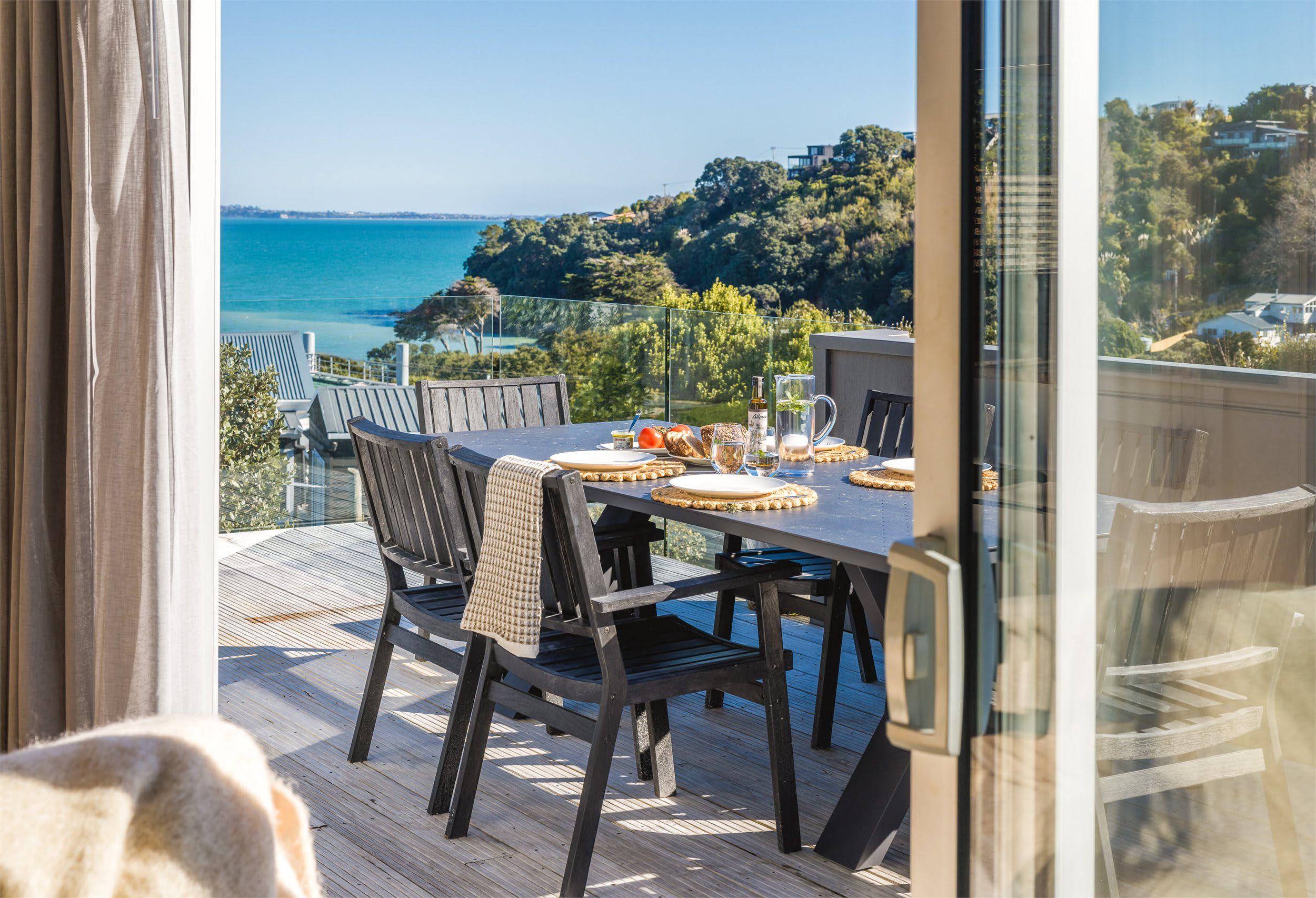 A dining area with a table set for four, overlooking a coastal view.