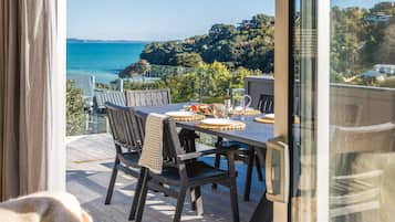 A dining area with a table set for four, overlooking a coastal view.