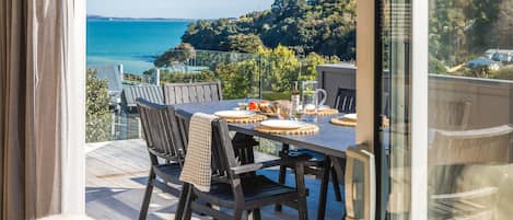 Comedor con una mesa dispuesta para cuatro personas, con vistas a la costa.