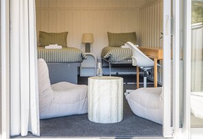 Een kleine hotelkamer met twee bedden, een tafeltje en twee stoelen.