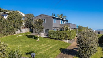 A modern two-story house with a well-maintained lawn and a wooden fence.